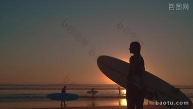 海边夕阳下拿着冲浪板的女孩